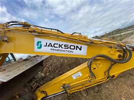 A digger arm with Jackson Remediation logo