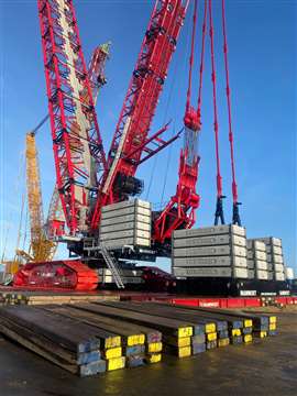 rear view of a big red crawler crane with grey counterweight slabs