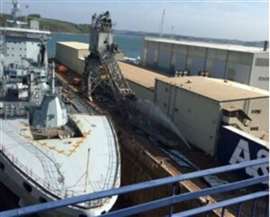 grey ship next to collapsed crane